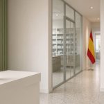 Couloir d’un hôpital espagnol menant au service de pharmacie, panneau « Servicio de Farmacia », drapeau espagnol discret au fond et flacon blanc marqué d’une feuille de cannabis au premier plan